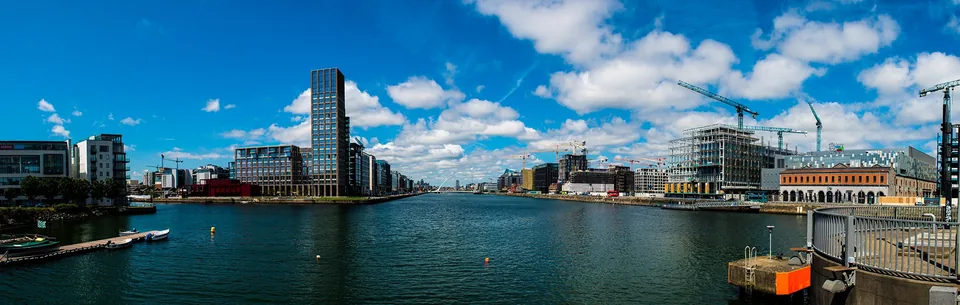 Panoramic view of waterfront buildings under a blue sky.